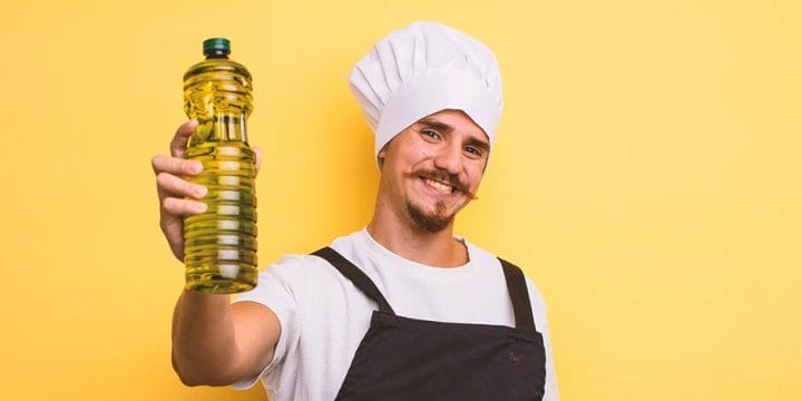 A male chef holding up a bottle of olive oil
