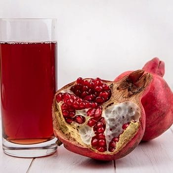 A slice of Pomegranate fruit and a juice in a glass