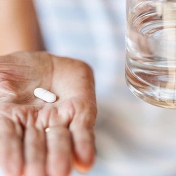 Holding a single white capsule on hand