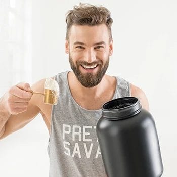 Man smiling while holding scoop of pre workout supplement