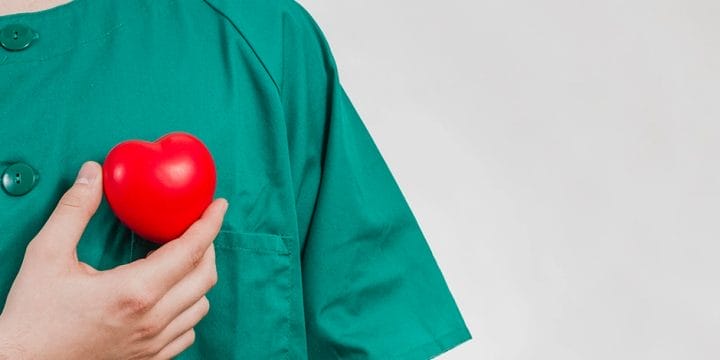 Nurse holding a small heart shaped toy representing cholesterol