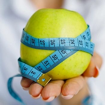 Holding a green apple with tape measure