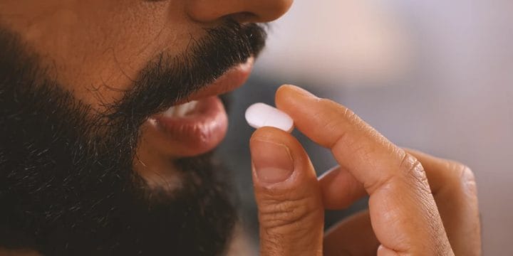 Close up shot of a person taking in night time recovery pills that boost muscle growth