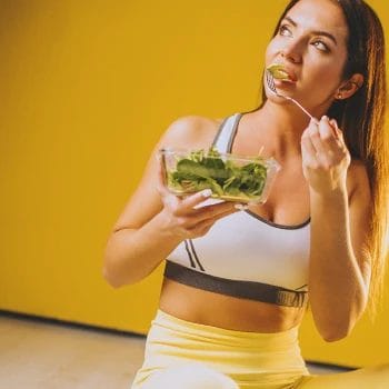 A woman holding a glass bowl of salad