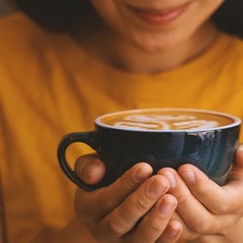 A woman holding a hot cup of coffee