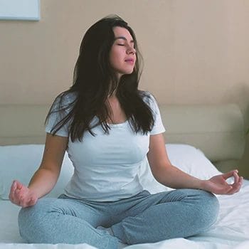A woman meditating on the bed