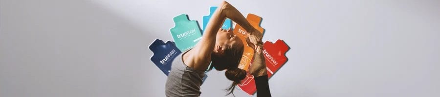 A woman doing yoga stretches with TruBrain nootropic supplement stack at the background