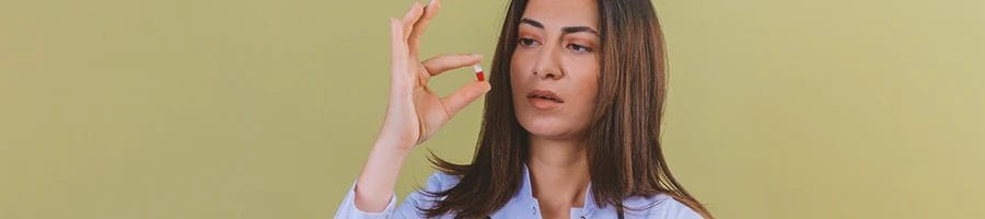 A person holding up a pill of nootropic close to her face