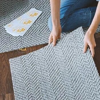 A woman installing carpet tiles at home