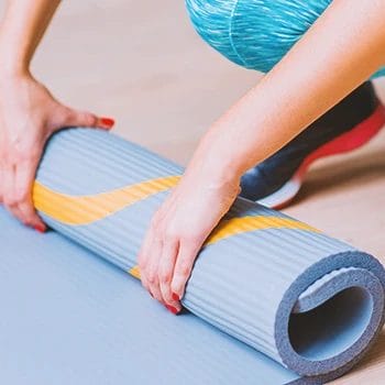 A woman rolling gym flooring at home