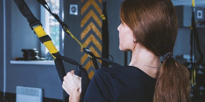 A woman tightening the cables at home gym equipment
