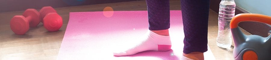 Woman stepping on a yoga mat with dumbbells and kettlebell