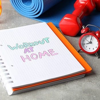 Workout at home notes with a clock beside the notebook