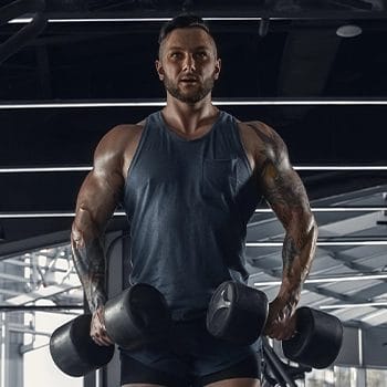 Man standing doing shrugs holding dumbbells with both hands