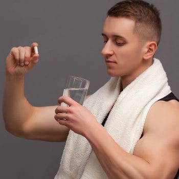 Man holding nootropic supplement while holding a glass of water