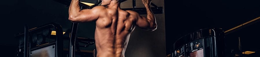 Man with good back muscles doing pull ups in his own home gym