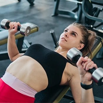 Woman doing dumbbell bench press