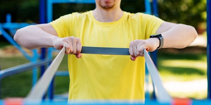 Man holding resistance band looped on a bar