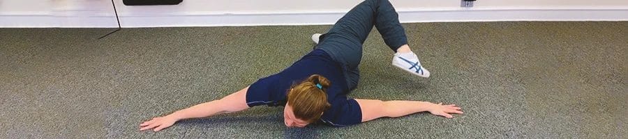 A woman doing a scorpion stretch on the ground