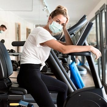 Woman with facemask riding on a recumbent bike
