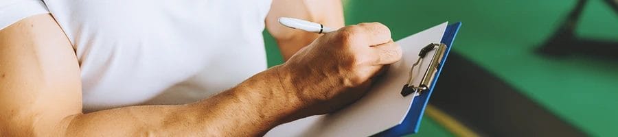 A gym coach writing down on a clipboard