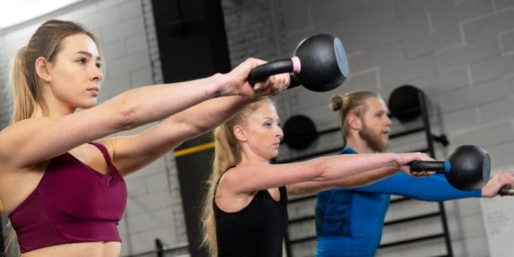 Performing kettlebell workout with gym buddies
