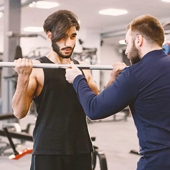 A coach helping a person in the gym workout