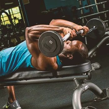 A buff male doing skull crusher workout in the gym