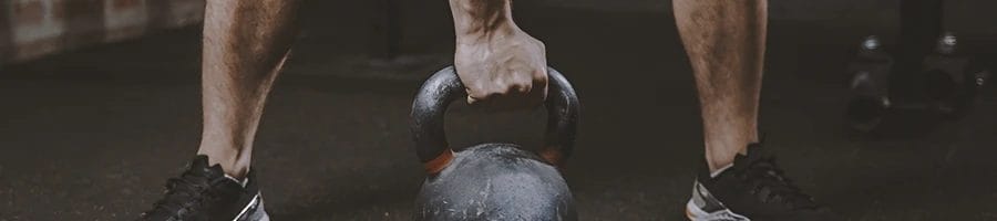 A person lifting up a kettleball and doing free-weight only workout routines