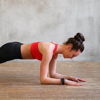 Woman in red workout attire performing plank up downs