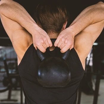 A person doing back workouts in the gym with a kettleball
