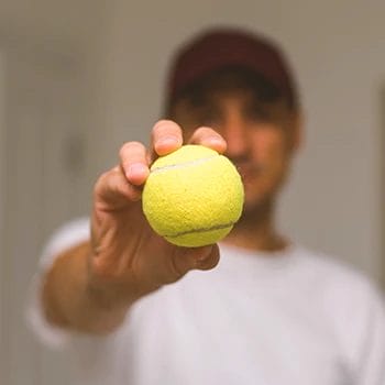 A person holding a tennis ball to the camera