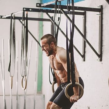 A person working out with gym rings tied to a pull up bar