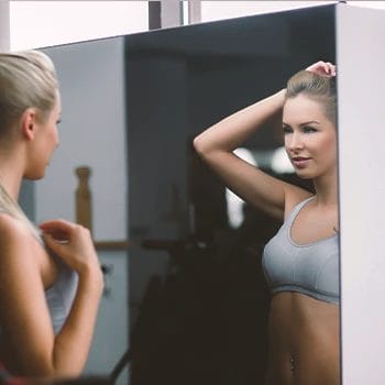 A woman in a home gym looking at a mirror