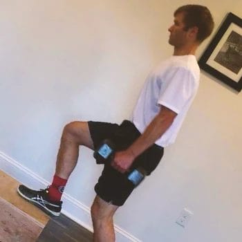 A person at home doing single leg dumbbell step ups