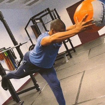 A person doing single leg deadlifts with a medicine ball