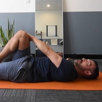 Man doing supine glute stretch indoor