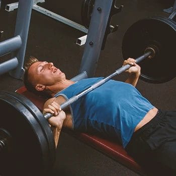 A buff male doing bench presses in the gym